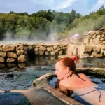 Turista en aguas termales de Salto, Uruguay, rodeada de naturaleza, representando turismo de bienestar y tradición curativa.