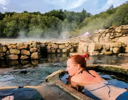 Turista en aguas termales de Salto, Uruguay, rodeada de naturaleza, representando turismo de bienestar y tradición curativa.