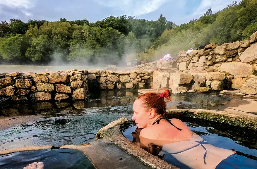 Turista en aguas termales de Salto, Uruguay, rodeada de naturaleza, representando turismo de bienestar y tradición curativa.