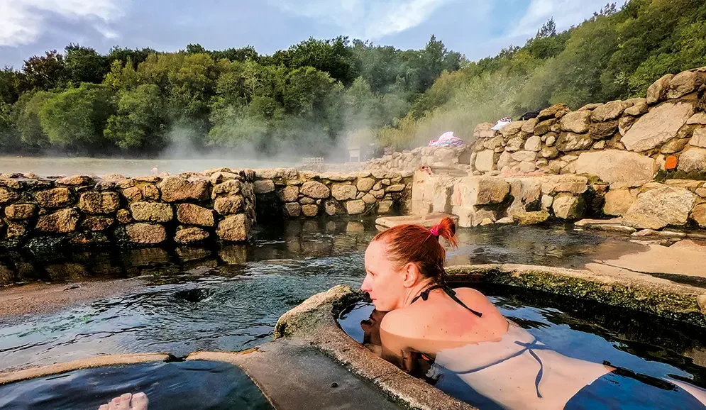 Turista en aguas termales de Salto, Uruguay, rodeada de naturaleza, representando turismo de bienestar y tradición curativa.