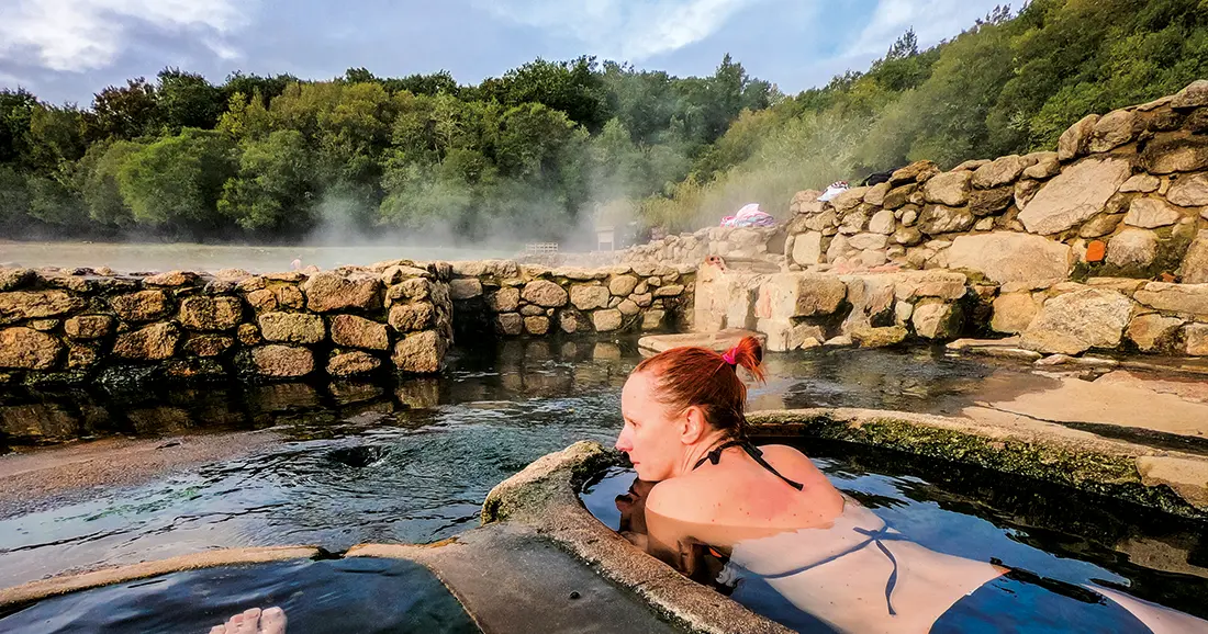 Turista en aguas termales de Salto, Uruguay, rodeada de naturaleza, representando turismo de bienestar y tradición curativa.